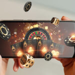 Creative background, online casino, in a man's hand a smartphone with playing cards, roulette and chips, black-gold background. Internet gambling concept. Copy space